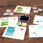 postcards and game pieces including a stamp and stamp pad on a brown wooden table