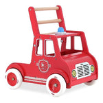 A red wooden toy fire truck walker with a natural wood handle, white wheels, and a small blue siren button, shown on a plain white background.
