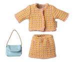 Set of yellow textured jacket, skirt, and blue handbag on a white background