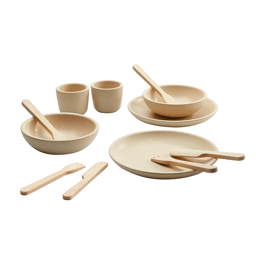 Set of beige dishes with wooden utensils on a white background