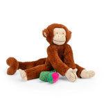 Plush monkey toy holding a green and pink object on a white background