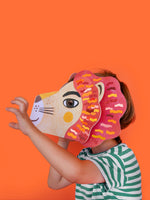Child wearing a colorful lion mask against an orange background