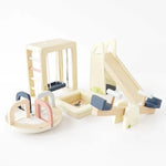 A wooden children's play set with multiple natural wood pieces including a ladder, slide, seesaw, and circular wheel components, accented with dark blue and pastel pink pieces, photographed on a clean white background.