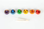 Set of colorful wooden bowls with small containers of multicolored objects on a white background
