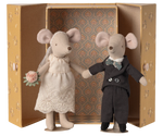 Two toy mice, one in a wedding dress and the other in a suit, standing in front of an ornate box.