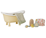 a miniature claw-foot bathtub with a towel hanging over the side and bath accessories next to it on a white background