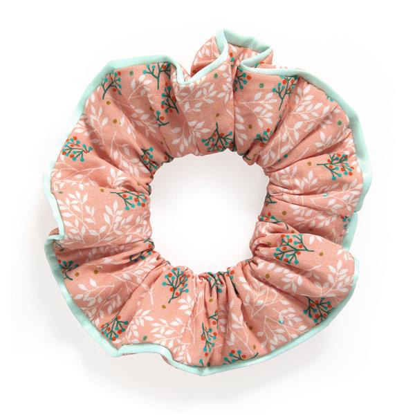 on a white background, a dusty pink scrunchie with delicate white and green sprigs and a light blue trim.