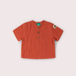 Orange children's shirt with buttons on a light beige background