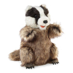 A plush stuffed animal shaped like a badger wearing a brown fur coat, sitting upright on a white background.