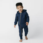 Child wearing a navy blue onesie with a gold zipper on a white background