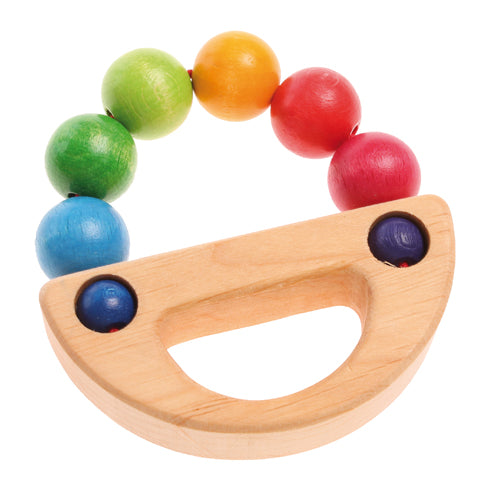 A wooden baby toy with rainbow balls in an arc that meets a natural wooden handle to create a circle on a white background.