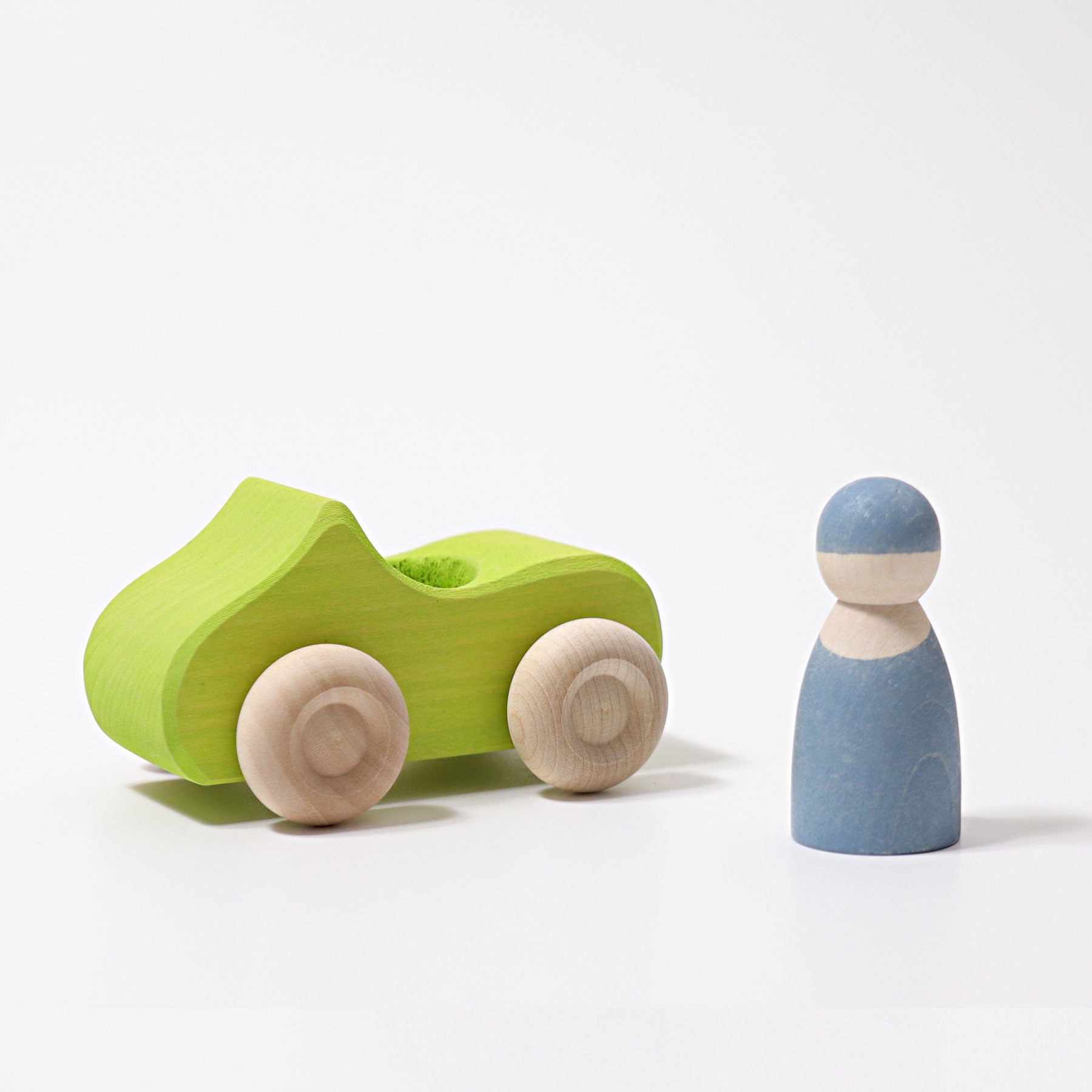 Small Green wooden Convertible Car next to a blue wooden peg doll on a white background.