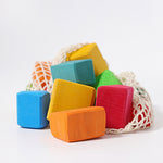 a bag of colourful wooden blocks in a net bag in a white setting.