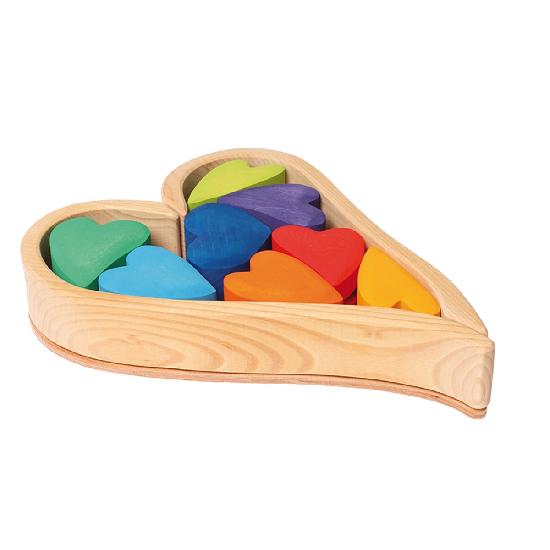 rainbow coloured hearts stored in a natural heart-shaped wooden frame on a white background