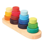 on a white background, four stacks of multi coloured discs on a natural wooden base.