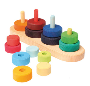 on a white background, four stacks of multi coloured discs on a natural wooden base. Some discs are removed to reveal posts that each stack of discs sits on.