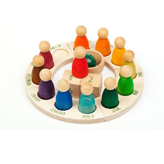 on a white background, a wooden perpetual ring calendar with a different coloured peg doll for each month of the year