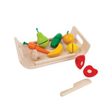 wooden fruits and vegetables on a wooden tray on a white background. a cut wooden apple and a wooden knife are next to it.