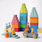 An assortment of rainbow and pastel building blocks and peg people with one car on a white background