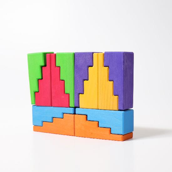 Rainbow coloured stepped building blocks pieced together to creat a rectangular tower on a white background