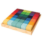 on a white background, a set of colourful rainbow wooden cubes in a natural wood tray.