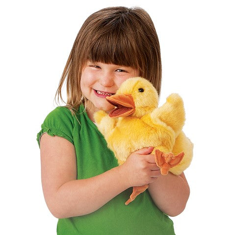 Alittle brown haired girl with bangs hugging a yellow plush duckling