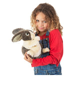 a girl holding a brown and cream plush dutch bunny on a white background