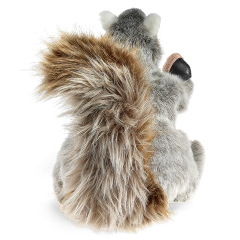 The back of a plush squirrel holding an acorn on a white background