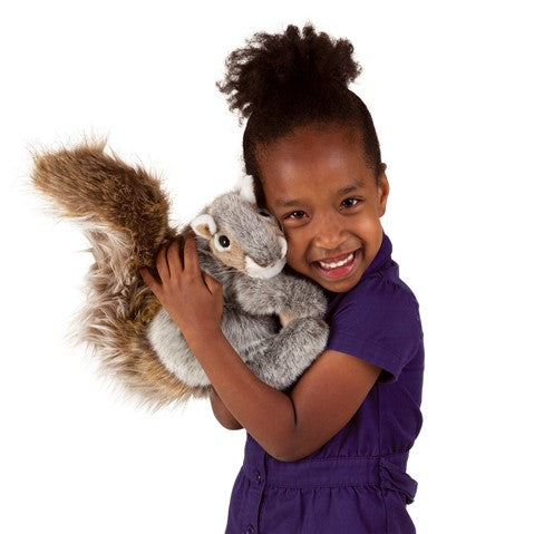 A smiling girl hugging a plush squirrel close to her face on a white background.