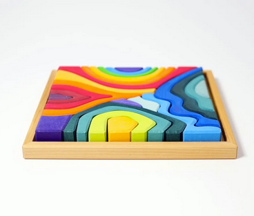 on a white background, a natural wood tray, filled with a wooden rainbow coloured puzzle in the shape of the four elements.