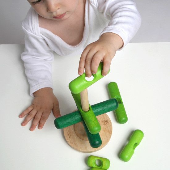 A baby playing with the stacking tree on a white background.