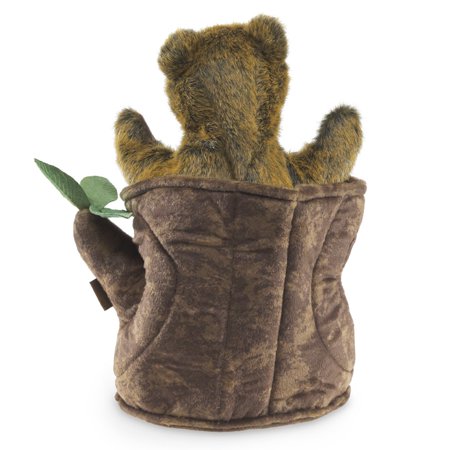 The back of a brown, plush bear cub in a soft tree stump with three green leaves on a white background.