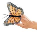 On a white background, a sheer, monarch butterfly finger puppet on a person's hand 