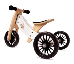 A wooden trike with natural and white colours and black wheels. No pedals