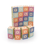 A set of lower case alphabet blocks stacked in a curved wall on a white background with a shorter wall in front. Some blocks show letters and some show numbers with different colours on each face.